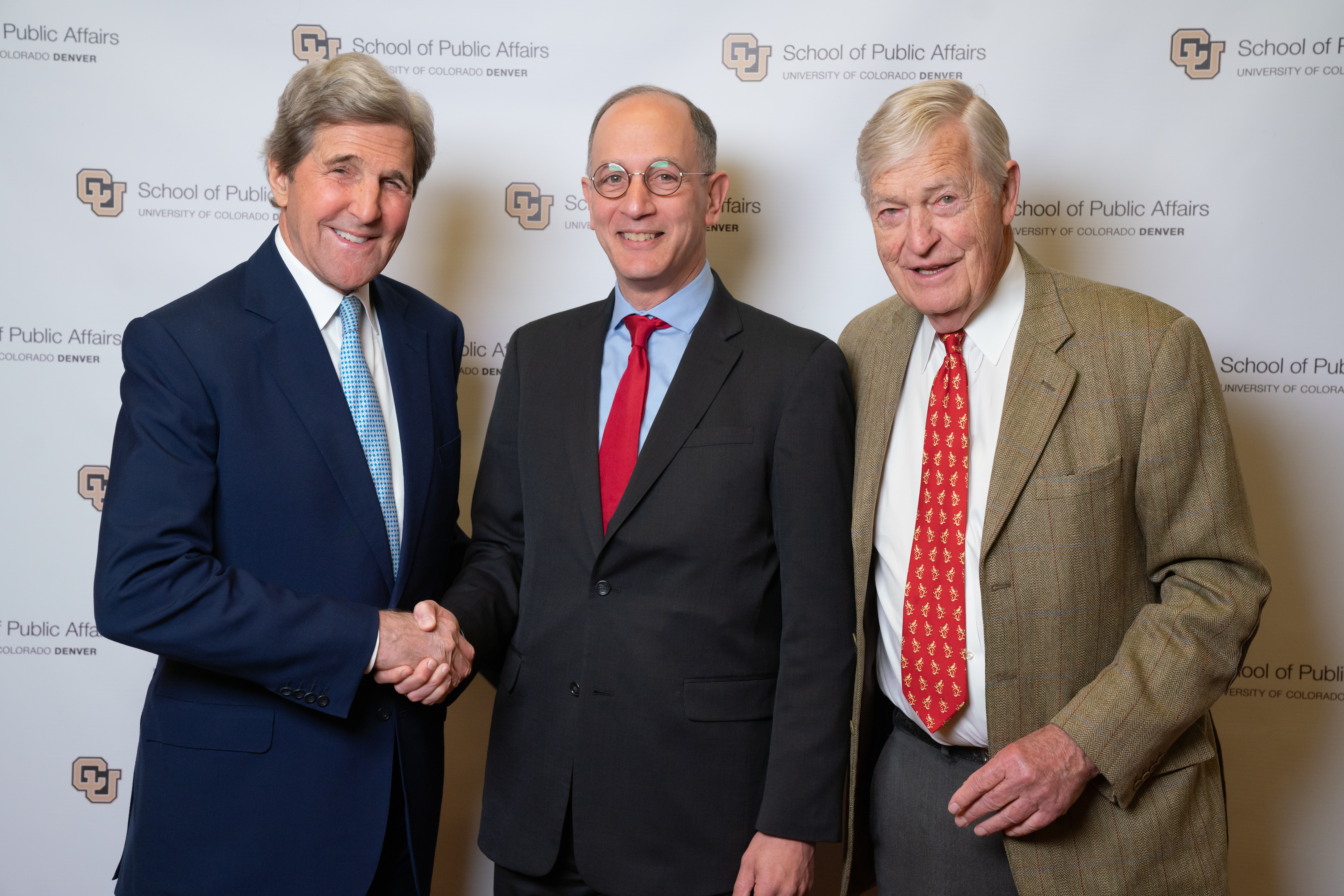 Jerry Tinianow shaking hands with former Secretary of State John Kerry and former Colorado Senator Tim Wirth standing next to them